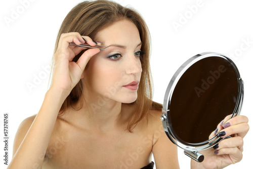 Photo: Young woman plucking eyebrows isolated on white Young woman plucking eyebrows isolated on white