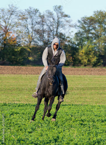 Photo: Man riding black horce on field Man riding black horce on field