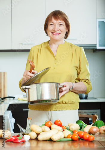 Photo: mature woman cooking vegetarian lunch mature woman cooking vegetarian lunch
