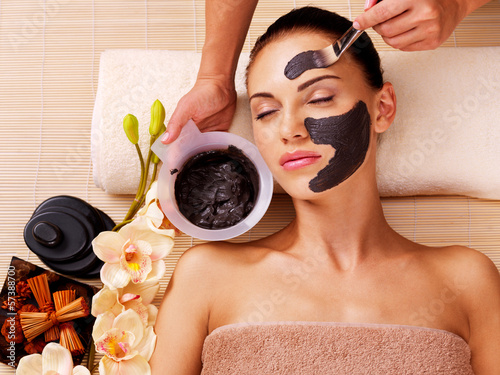 Photo: Cosmetologist smears cosmetic mask on the face of woman Cosmetologist smears cosmetic mask on the face of woman