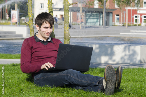 Photo: junger mann mit laptop im park junger mann mit laptop im park