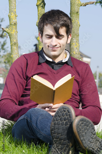 Photo: junger mann liest im park junger mann liest im park