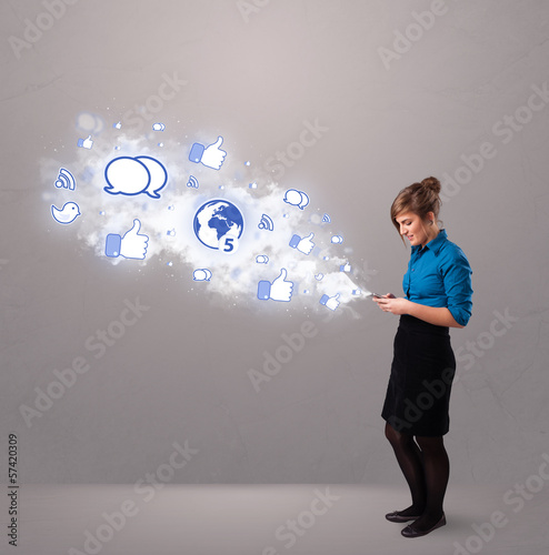 Photo: Pretty young girl holding a phone with social media icons Pretty young girl holding a phone with social media icons