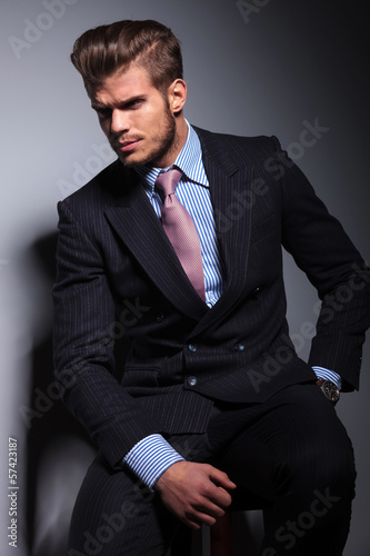 Photo: angry young business man in classic suit and tie sitting angry young business man in classic suit and tie sitting