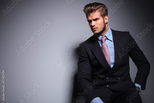 Photo: seated young fashion model in suit looks away seated young fashion model in suit looks away