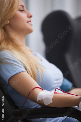 Photo: Smiling woman getting a transfusion and sitting on a chair Smiling woman getting a transfusion and sitting on a chair