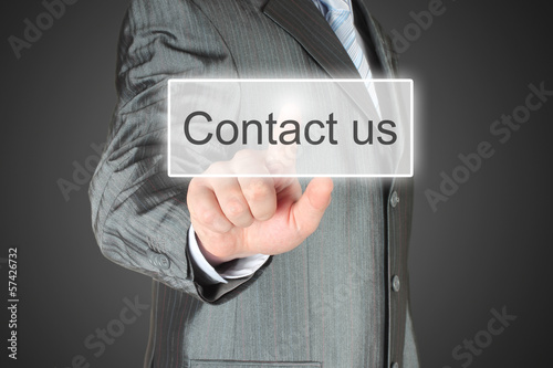 Photo: Businessman pushes virtual contact us button Businessman pushes virtual contact us button