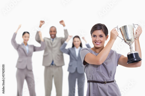 Photo: Woman holding up a cup with enthusiastic co-workers Woman holding up a cup with enthusiastic co-workers