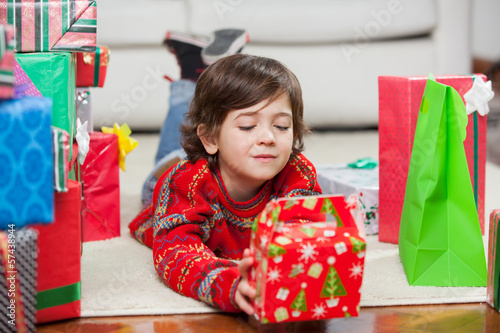 Photo: Boy With Christmas Present Lying On Floor Boy With Christmas Present Lying On Floor