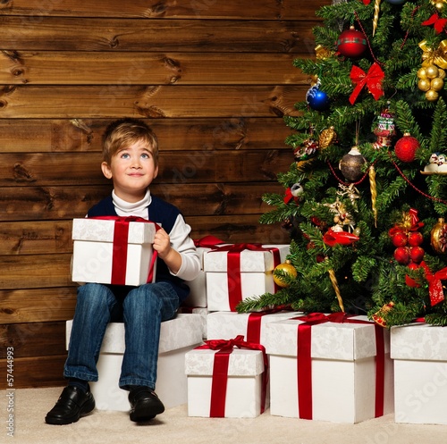 Photo: LIttle boy opening gift box under christmas tree LIttle boy opening gift box under christmas tree
