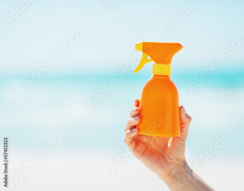 Photo: Closeup on bottle of sun screen creme in hand of woman Closeup on bottle of sun screen creme in hand of woman