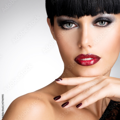 Photo: Face of a woman with beautiful dark nails and sexy red lips Face of a woman with beautiful dark nails and sexy red lips