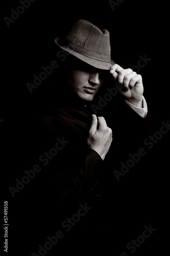 Photo: Portrait of young gangster with hat in the darkness Portrait of young gangster with hat in the darkness