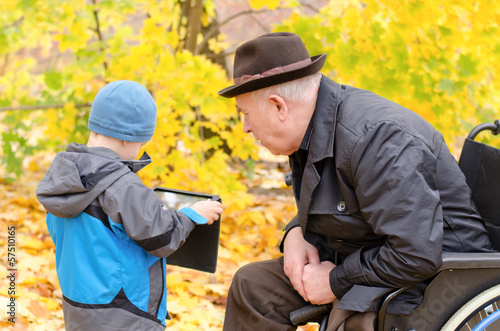 Photo: Boy using a tablet pc with grandfather watching Boy using a tablet pc with grandfather watching