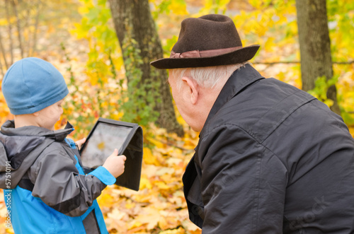 Photo: Boy using a tablet pc with grandfather watching Boy using a tablet pc with grandfather watching