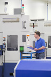 Photo: Technician with clipboard examining lathe cutting machine in hi-tech manufacturing plant Technician with clipboard examining lathe cutting machine in hi-tech manufacturing plant