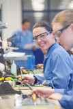 Photo: Portrait of smiling technician soldering circuit board on production line in manufacturing plant Portrait of smiling technician soldering circuit board on production line in manufacturing plant