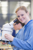 Foto: Portrait of smiling technician using microscope in circuit board manufacturing plant Portrait of smiling technician using microscope in circuit board manufacturing plant