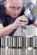 Photo: Portrait of smiling businessman in manufacturing plant with engineers in background Portrait of smiling businessman in manufacturing plant with engineers in background