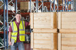 Photo: Portrait of smiling supervisor examining machine part in bin on production line in distribution warehouse Portrait of smiling supervisor examining machine part in bin on production line in distribution warehouse