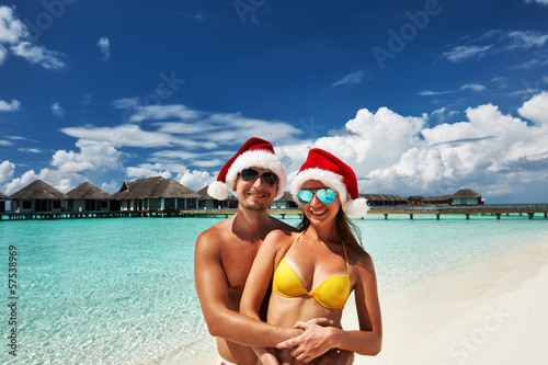 Photo: Couple in santa's hat on a beach at Maldives Couple in santa's hat on a beach at Maldives