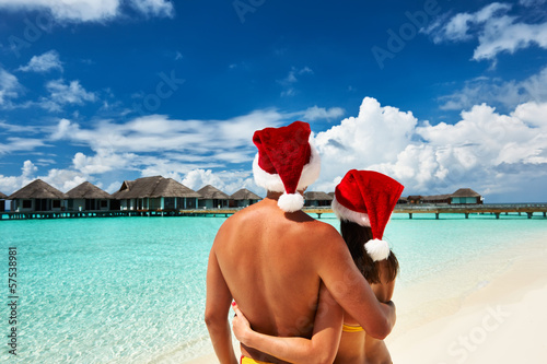 Photo: Couple in santa's hat on a beach at Maldives Couple in santa's hat on a beach at Maldives