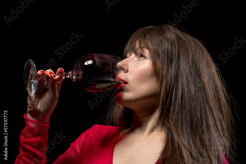Photo: Young woman drinking red wine from a glass Young woman drinking red wine from a glass