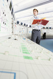 Photo: Engineer with binder looking up at computer monitor in control room of nuclear power station Engineer with binder looking up at computer monitor in control room of nuclear power station