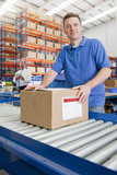 Photo: Portrait of worker with cardboard box on production line in distribution warehouse Portrait of worker with cardboard box on production line in distribution warehouse
