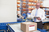 Foto: Supervisor using digital tablet next to cardboard box on production line in distribution warehouse Supervisor using digital tablet next to cardboard box on production line in distribution warehouse