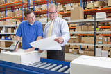 Photo: Supervisor and worker examining paperwork and scanning boxes on production line in distribution warehouse Supervisor and worker examining paperwork and scanning boxes on production line in distribution warehouse