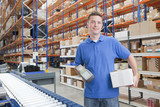 Photo: Portrait of smiling worker holding scanner and box at production line in distribution warehouse Portrait of smiling worker holding scanner and box at production line in distribution warehouse