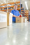 Photo: Portrait of smiling worker taping cardboard boxes on production line in distribution warehouse Portrait of smiling worker taping cardboard boxes on production line in distribution warehouse