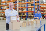 Photo: Portrait of smiling supervisor leaning on box on production line in distribution warehouse Portrait of smiling supervisor leaning on box on production line in distribution warehouse