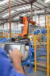 Foto: Worker controlling robotic machinery lifting steel fencing on production line in manufacturing plant Worker controlling robotic machinery lifting steel fencing on production line in manufacturing plant