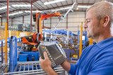 Foto: Close up of worker controlling robotic machinery lifting steel fencing on production line in manufacturing plant Close up of worker controlling robotic machinery lifting steel fencing on production line in manufacturing plant