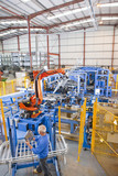Photo: Worker controlling robotic machinery lifting steel fencing on production line in manufacturing plant Worker controlling robotic machinery lifting steel fencing on production line in manufacturing plant