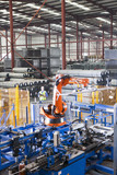 Photo: Worker controlling robotic machinery lifting steel fencing on production line in manufacturing plant Worker controlling robotic machinery lifting steel fencing on production line in manufacturing plant