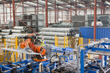 Photo: Worker controlling robotic machinery lifting steel fencing on production line in manufacturing plant Worker controlling robotic machinery lifting steel fencing on production line in manufacturing plant