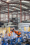 Photo: Worker controlling robotic machinery lifting steel fencing on production line in manufacturing plant Worker controlling robotic machinery lifting steel fencing on production line in manufacturing plant