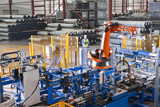 Photo: Worker controlling robotic machinery lifting steel fencing on production line in manufacturing plant Worker controlling robotic machinery lifting steel fencing on production line in manufacturing plant