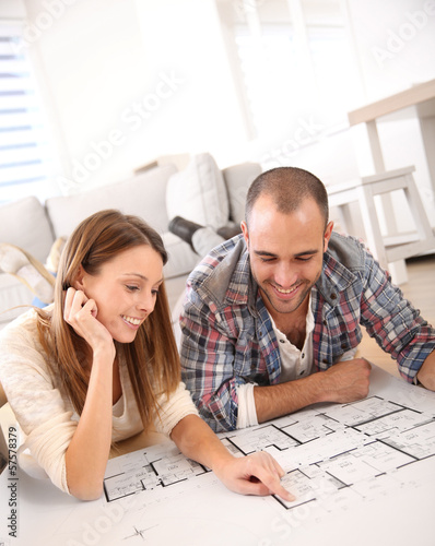Photo: Cheerful couple looking at construction house plan Cheerful couple looking at construction house plan