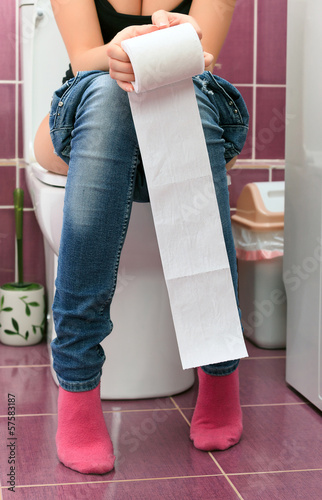 Photo: Woman in a toilet with a big hank of sanitary paper Woman in a toilet with a big hank of sanitary paper