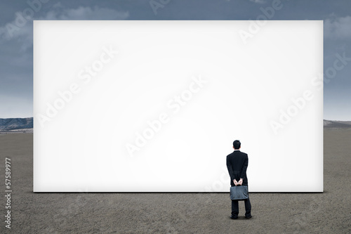 Photo: Businessman is looking at empty board Businessman is looking at empty board