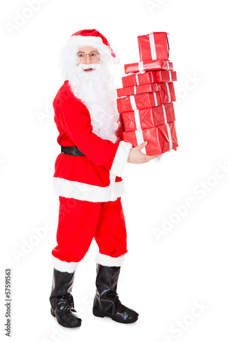 Photo: Portrait of santa holding stack of gift Portrait of santa holding stack of gift