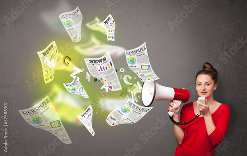 Photo: Girl yelling into loudspeaker and newspapers fly out Girl yelling into loudspeaker and newspapers fly out