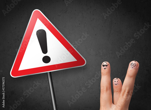 Photo: Happy smiley fingers looking at triangle warning sign with excla Happy smiley fingers looking at triangle warning sign with excla