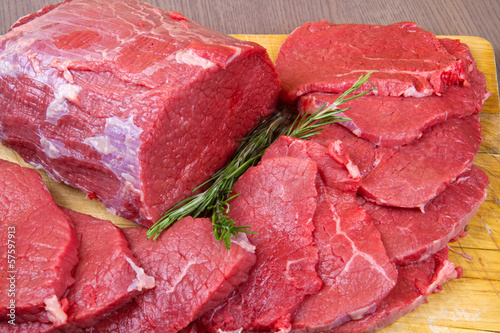 Photo: huge red meat chunk and steak isolated over wood background huge red meat chunk and steak isolated over wood background
