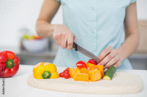 Photo: Mid section of young slender woman cutting vegetables Mid section of young slender woman cutting vegetables