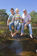 Photo: Portrait of smiling multi-generation family sitting barefoot on footbridge over stream Portrait of smiling multi-generation family sitting barefoot on footbridge over stream